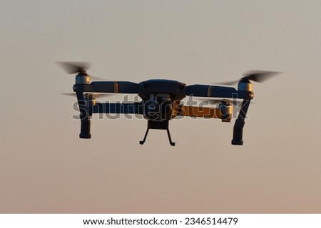 Drone quad copters with high resolution digital camera flying aerial over spectacular sunset orange sky