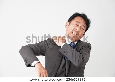 Asian middle aged businessman having stiff shoulders in white background Royalty-Free Stock Photo #2346529395