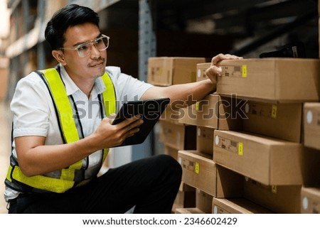 A warehouse worker uses a laptop to check the boxes in a warehouse warehouse full of boxes. Industrial Warehouse.