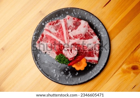 Thinly sliced beef on a black plate ready for shabu and yakiniku dishes.
