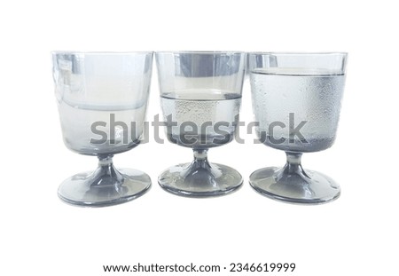 a photography of three glasses of water sitting on top of each other, three glasses of water are sitting on a table.