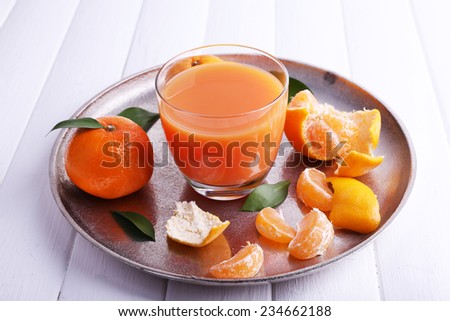 Glass of juice and ripe sweet tangerine on wooden table