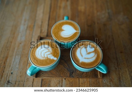 Close-up of three green coffee cappuccino cups with latte art on a wooden table