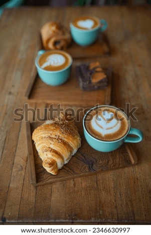 Close-up of three cups of green coffee cappuccino with latte art and cookies on a wooden table