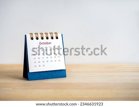 An October 2023 calendar desk for the organizer to plan and reminder isolated on wood table and white background with copy space, minimal style. Blue small table calendar with page of the 10th month.