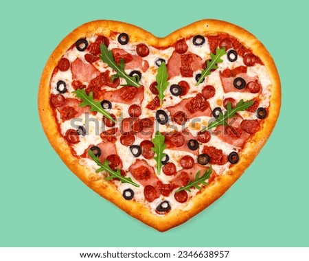 appetizing heart shaped pizza with ham and hunting sausages on green background, studio shot