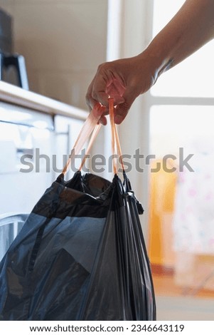 Hand removing black rubbish bag with debris from kitchen waste bin Royalty-Free Stock Photo #2346643119