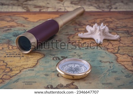 Brass compass, a spyglass and a starfish lie on an old map. Close-up