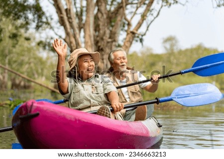 Asian senior couple kayaking together in the lake at mangrove forest on summer vacation. Retired elderly people man and woman have fun outdoor lifestyle travel nature and rowing a boat in the river. Royalty-Free Stock Photo #2346663213