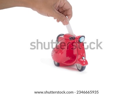 south east asian hand saving money to a ceramic fat red scooter piggy bank in isolated white