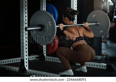 Back view, woman lifting weight, squatting with barbell in gym, sporty woman exercising  Royalty-Free Stock Photo #2346668091