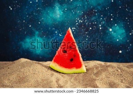 Slice of juicy ripe watermelon on the beach against the background of the starry sky.