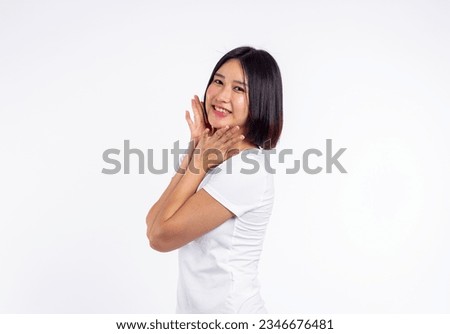 Young woman of asian smiling face in a white t-shirt smiles happily hands touch cheek smile, on white background, portrait concept.

