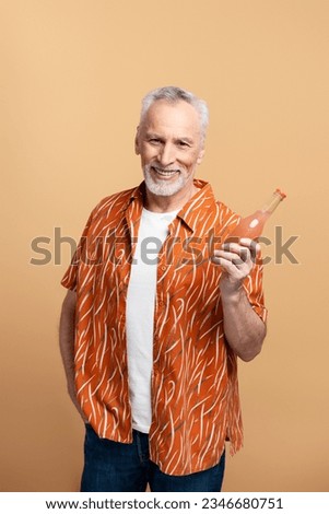 Portrait of smiling mature man wearing stylish orange shirt and white t shirt holding lemonade isolated on beige background. Positive lifestyle, summer travel concept