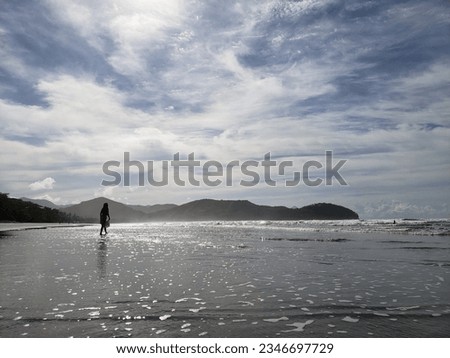 Woman walking on the beach with sunset in the background