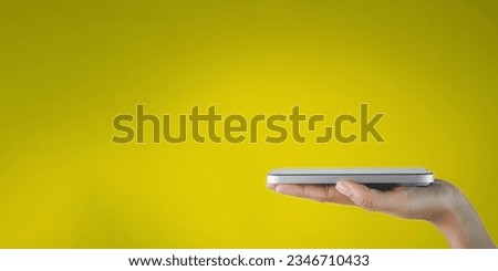 Mock up,Object concept.,Woman hand holding smartphone with screen face up over yellow background with copyspace suitable for technology,banner,business,background idea.