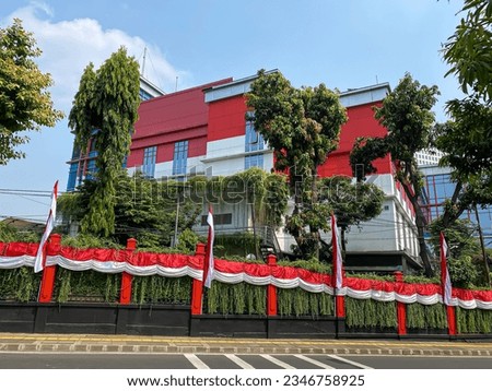 building with red and white paint and Indonesian red and white flag on the yard fence ahead of independence day