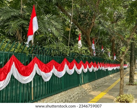 Indonesian red and white flags and banners on the yard fence and sidewalk ahead of independence day