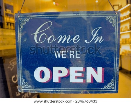Come in we're open sign in front of a small shop