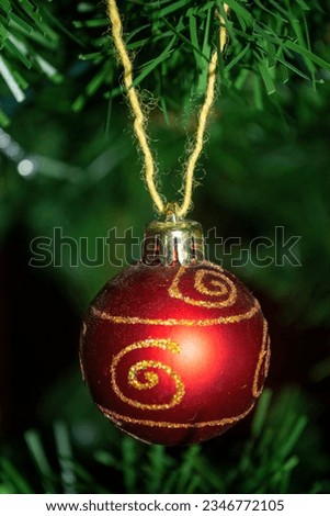 A ball on the tree. A red ball with a golden blister on the Christmas tree. Toy for the New Year tree