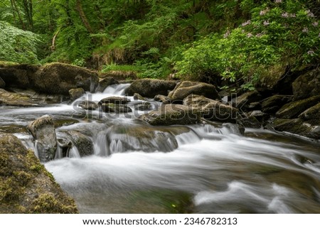 Long exposure of a waterfall on the East Lyn river flowing through the woods at Watersmeet in Exmoor National Park