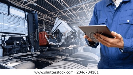 Serviceman with digital tablet on the background of the truck in the garage. Royalty-Free Stock Photo #2346784181