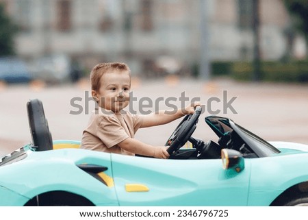 Little novice driver, happy child boy driving car outdoor. Royalty-Free Stock Photo #2346796725