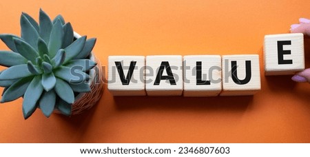 Value symbol. Concept word value on wooden cubes. Businessman hand. Beautiful orange background with succulent plant. Business and value concept. Copy space.