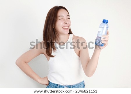 woman holding bottle of water standing over isolated background. Royalty-Free Stock Photo #2346821151