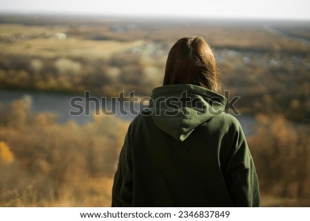 Rear view of trendy young woman in dark green hoodie in autumn copy space. Cute model walks in park in golden autumn through colorful trees and fallen leaves. Autumn fall walk colorful nature Royalty-Free Stock Photo #2346837849