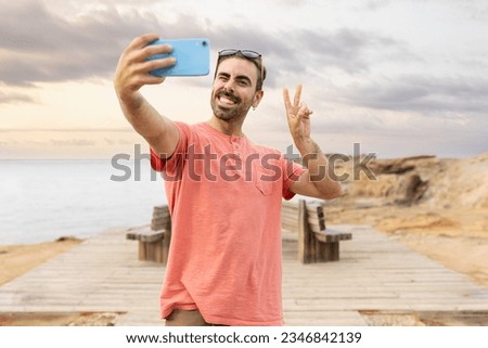 Man taking selfie on beach at sunset smiling looking at camera Royalty-Free Stock Photo #2346842139