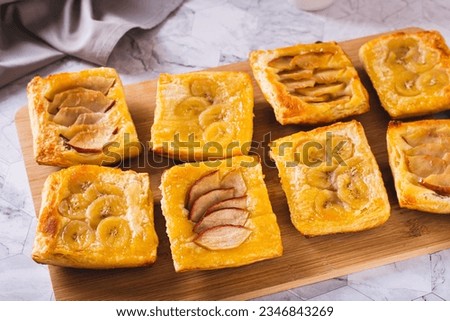 Small upside-down puff pastry cakes with banana and apple on a board Royalty-Free Stock Photo #2346843269