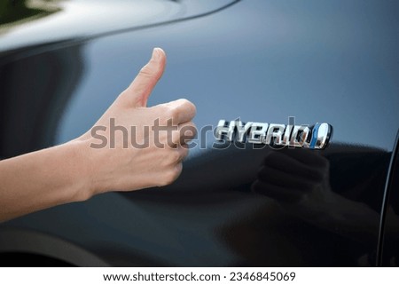 Purchaser hand showing thumb up sign at hybrid car new effective vehicle Royalty-Free Stock Photo #2346845069