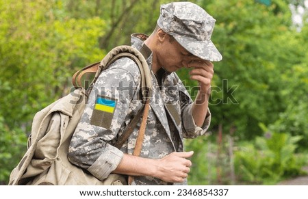 Ukrainian soldier wearing military uniform with flag and chevron depicting trident - Ukrainian national symbol flag