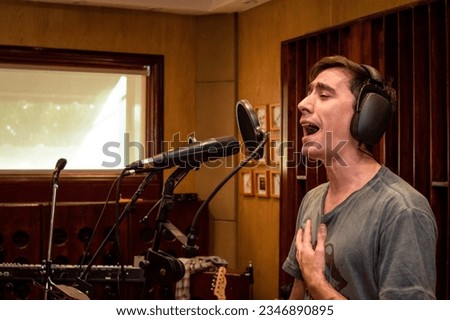 Professional singer in recording studio. Singer recording a single in the studio. Happy man singing. Professional singer. Copy space