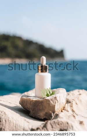 Cosmetic serum bottle on stone on the background of sea bay, closeup.