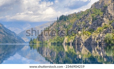 The picturesque lake of Sary Chelek. Amazing view of hills, mountains and rocks covered with green forests. The State Biosphere Reserve is a specially protected natural territory of Kyrgyzstan. Royalty-Free Stock Photo #2346904219