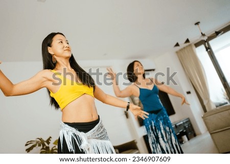 Picture of a group of female friends  performing Belly Dance in beautiful costumes. with fun at their homes, woman dance, Belly dancer in legging and hip scarf dancing. Royalty-Free Stock Photo #2346907609