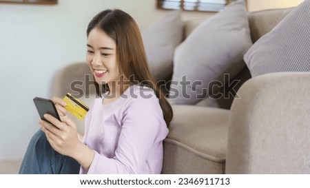 Women use smartphone and credit card to shopping online while sitting on floor in lifestyle at home.