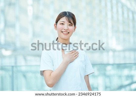 A woman in a white coat posing to put her hand on her chest