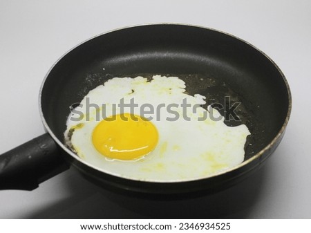 Fried sunny side up egg with yellow yolk in a black teflon. The picture was taken in a kitchen, in Indonesia, East Java.
