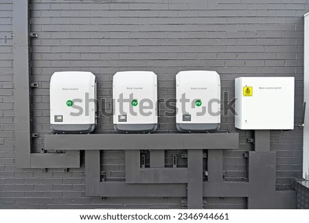 Three commercial size solar inverters and a control panel on a brick wall Royalty-Free Stock Photo #2346944661