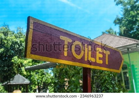 a wooden board indicating the direction to the toilet