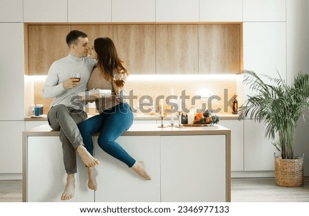 Young couple in love drinking red wine at kitchen. Cozy home. Love and romantic.