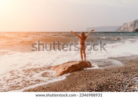 Woman summer travel sea. Happy tourist in red bikini enjoy taking picture outdoors for memories. Woman traveler posing on beach at sea surrounded by volcanic mountains, sharing travel adventure joy