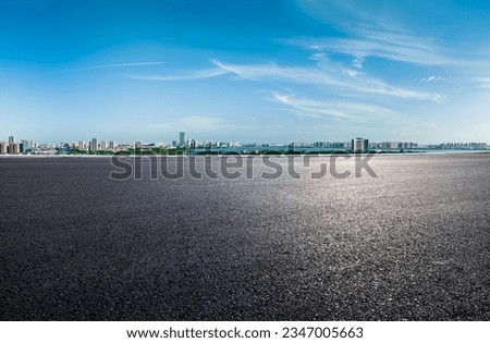 Asphalt road and urban skyline with sky clouds background