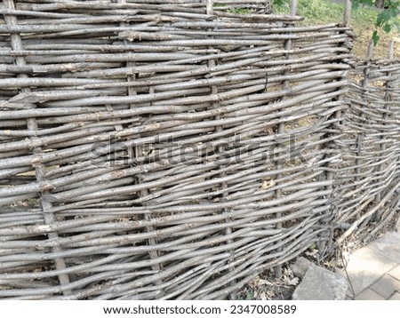 Fence made of flexible tree branches.  Wicker fence made of tree branches.  Rustic fence made of branches.