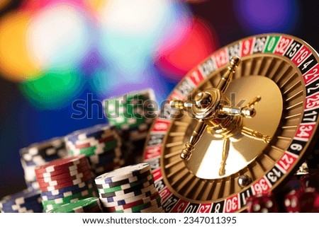 Casino theme. High contrast image of casino roulette, poker game, dice game, poker chips on a gaming table. Royalty-Free Stock Photo #2347011395