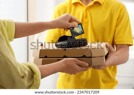 Young courier receiving payment for pizza from woman at doorway