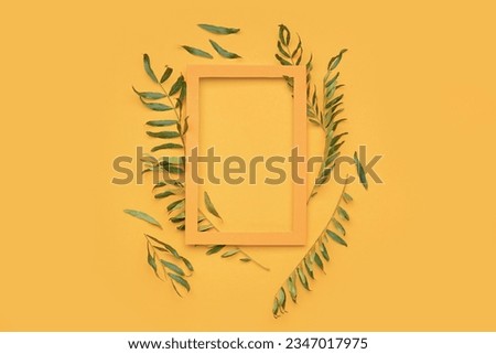 Composition with picture frame and plant leaves on color background